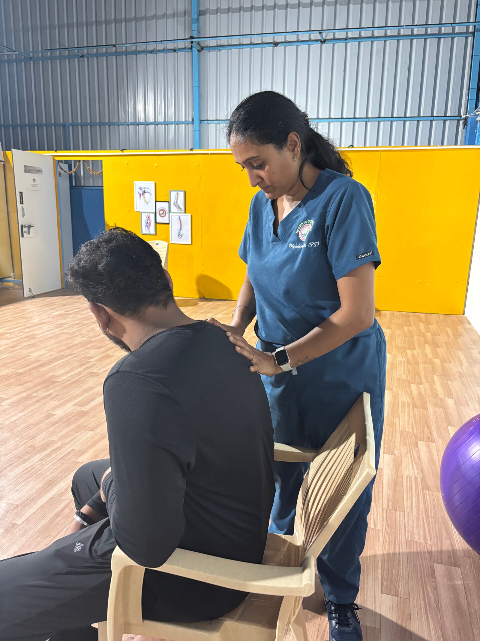 Priyadarshini treating a seated patient at Healthroughtouchh, Neotown